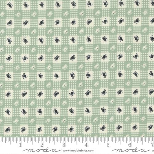 Fabric pattern with small black spiders on a light green checkered background, featuring Moda label.
