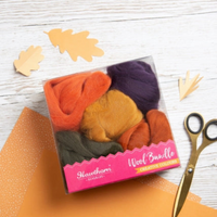 Wool bundle set with colorful wool bundles in a clear package on a wood background with scissors and fabric.