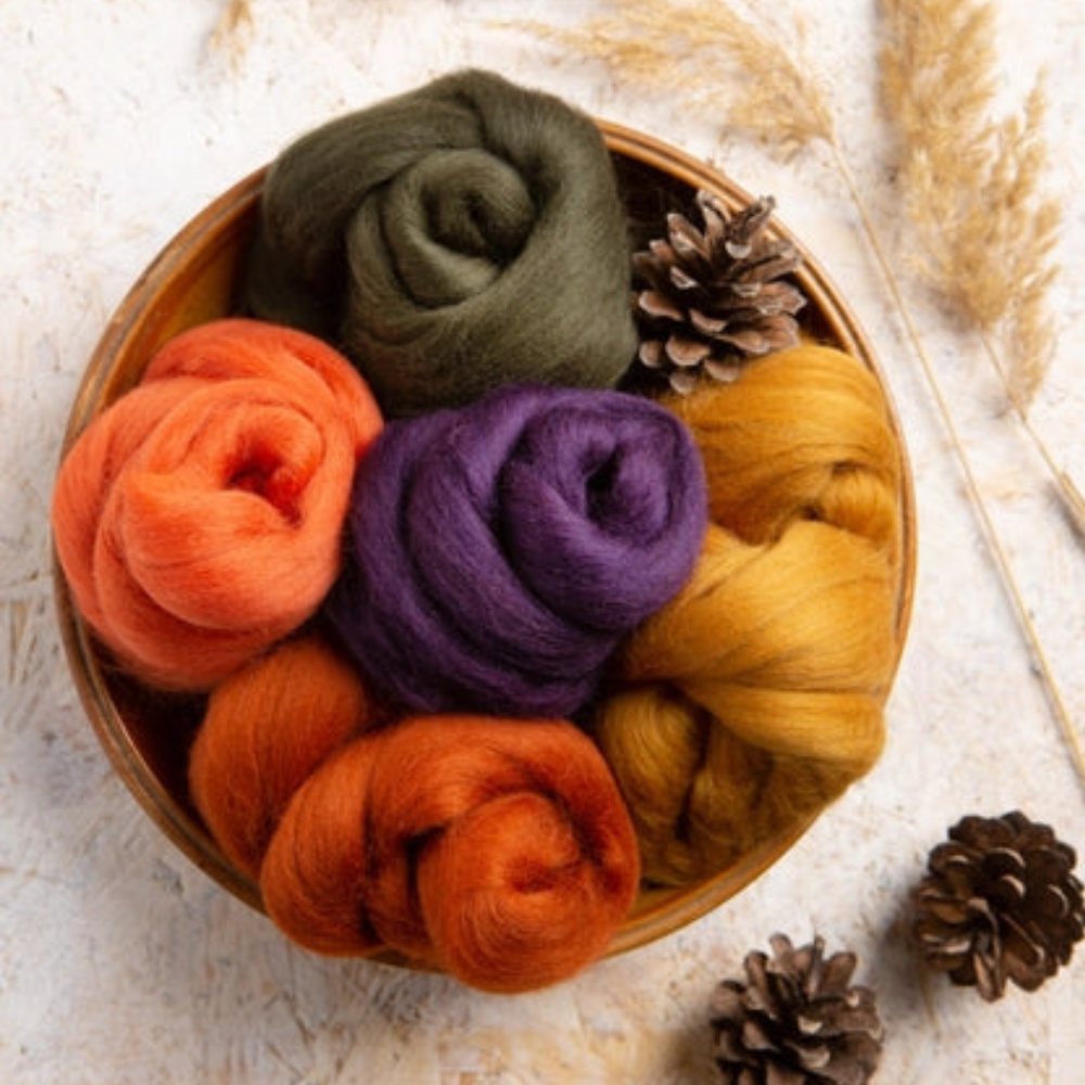 Wooden bowl with colorful wool bundles and pine cones on a light background