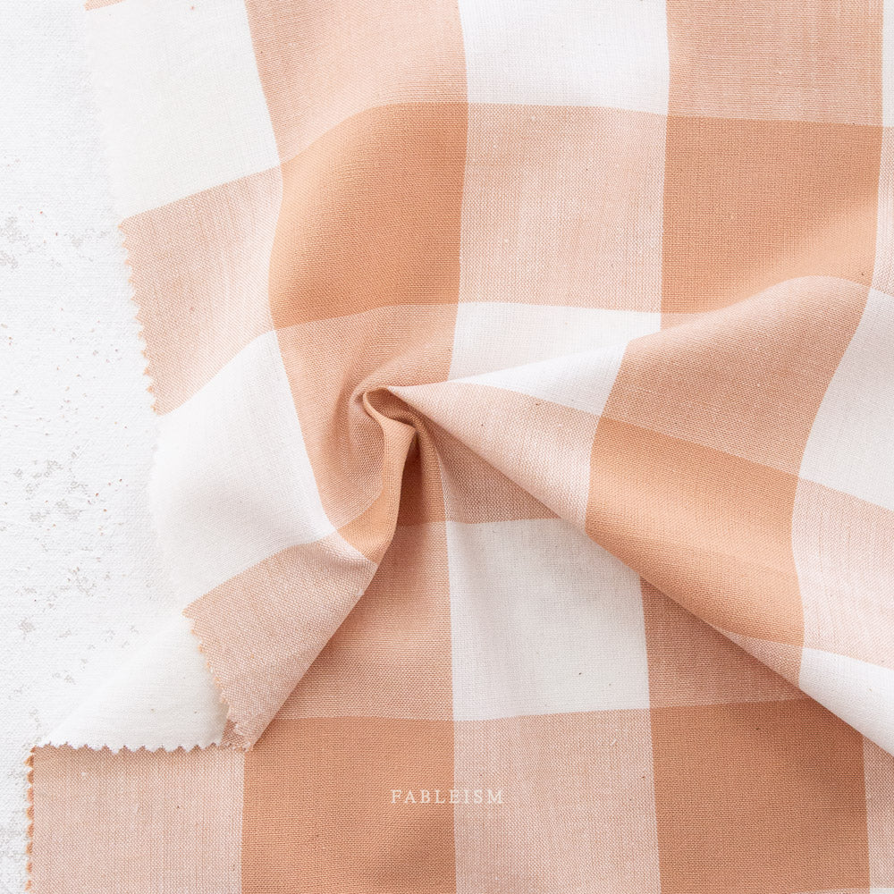Checkered fabric swatch with pink  and white pattern on a textured surface,