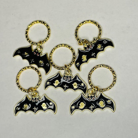Black enamel bats with gold outline and on a golden ring. Ghost and stars on wings and cross on body.