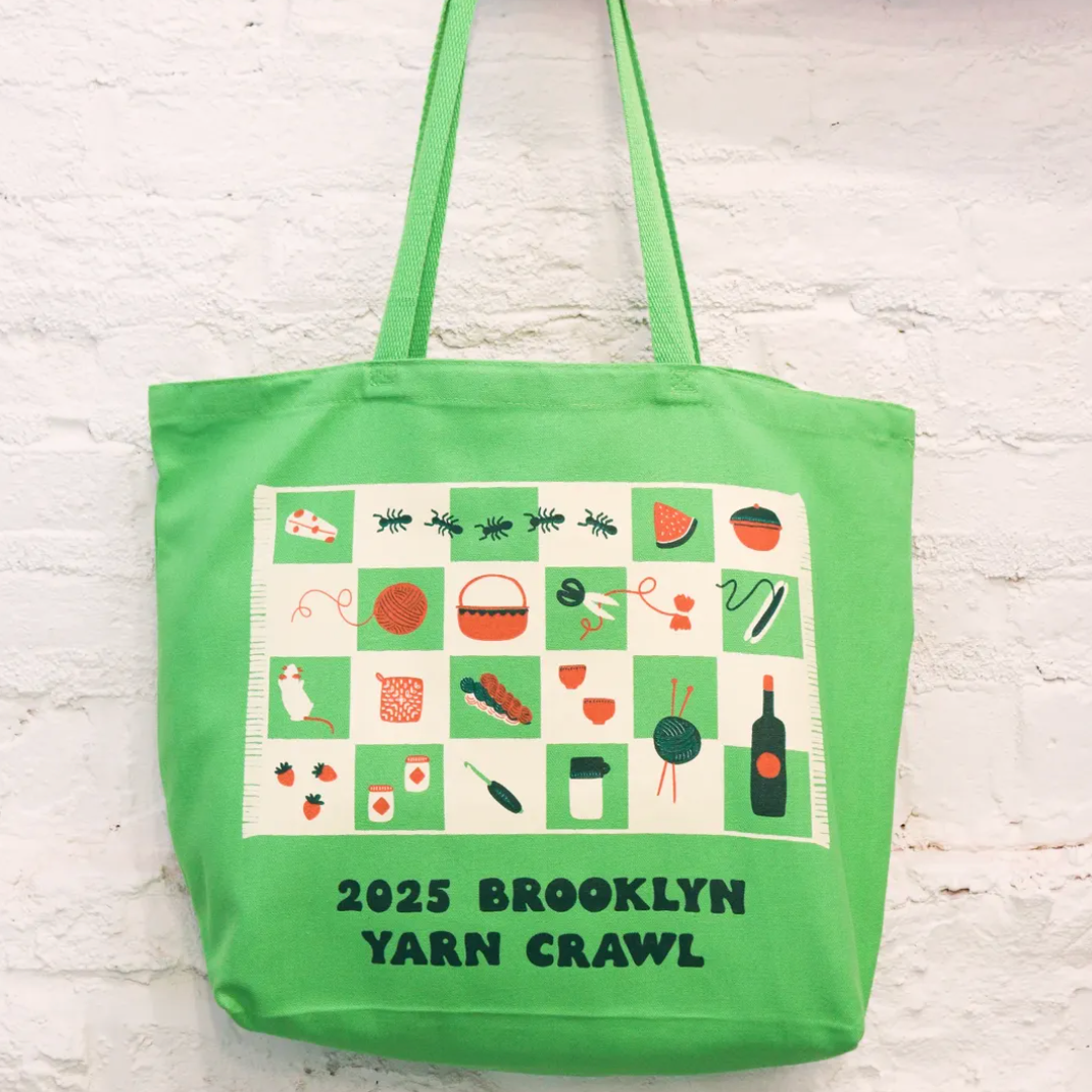 A bright green tote bag with a picnic blanket illustration and text that reads 2025 brooklyn yarn crawl
