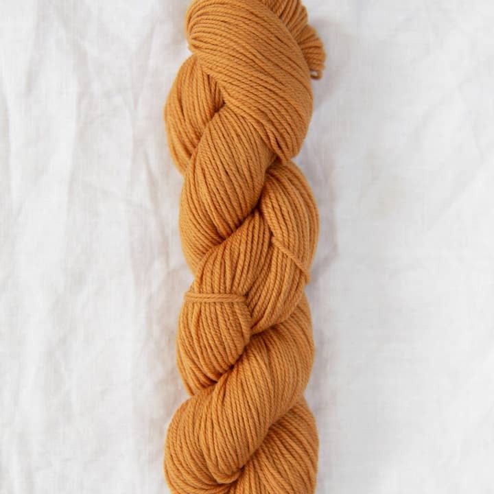 Braided mustard yellow yarn on a white background