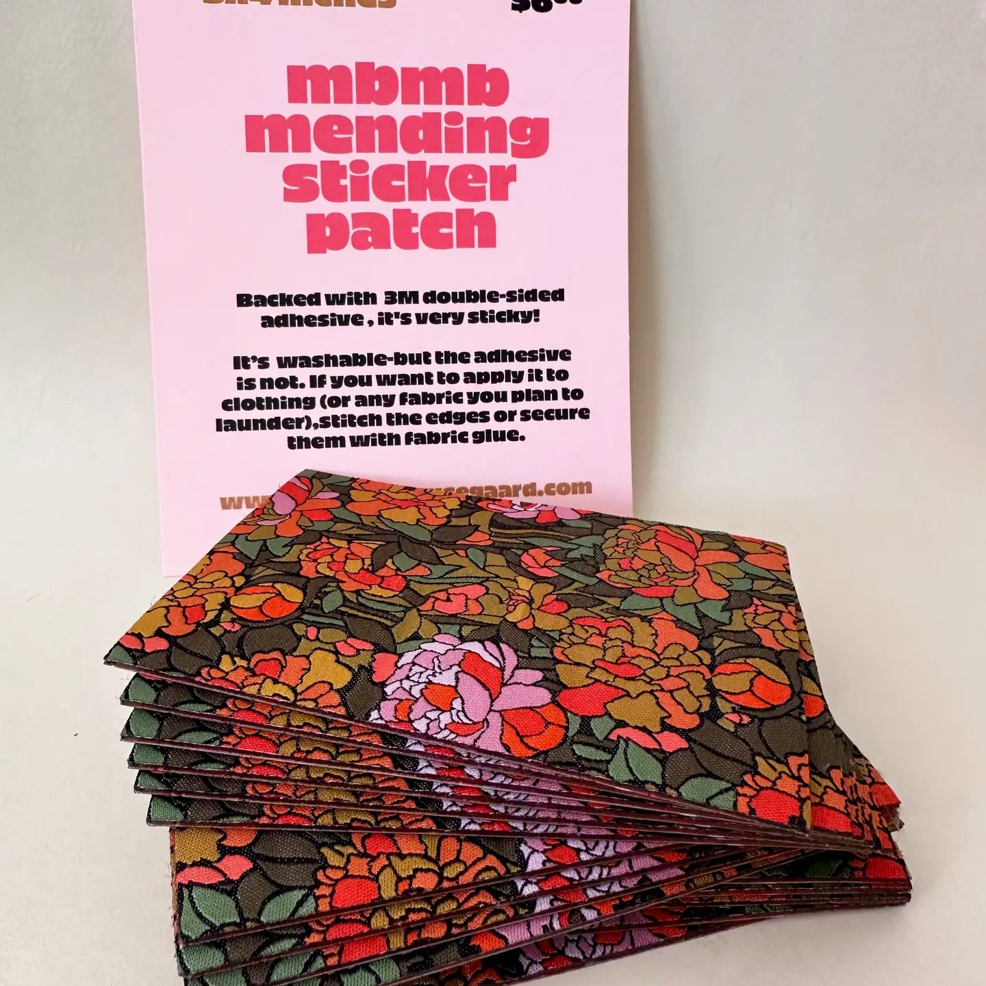 Stack of floral-patterned patches with a pink card detailing product information on a white background.