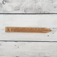 Wood with instructions for hand winding a yarn ball