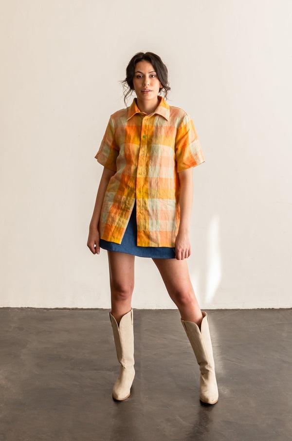 View from the front of a person wearing the short sleeve version of the Butano Button Up in an orange plaid fabric.