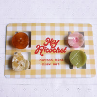 Set of 4 little hair clips that look like different buttons on their packaging