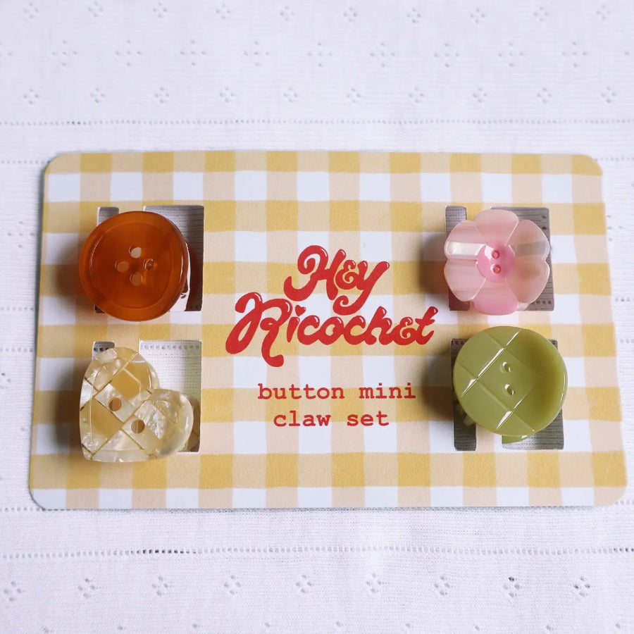 Set of 4 little hair clips that look like different buttons on their packaging