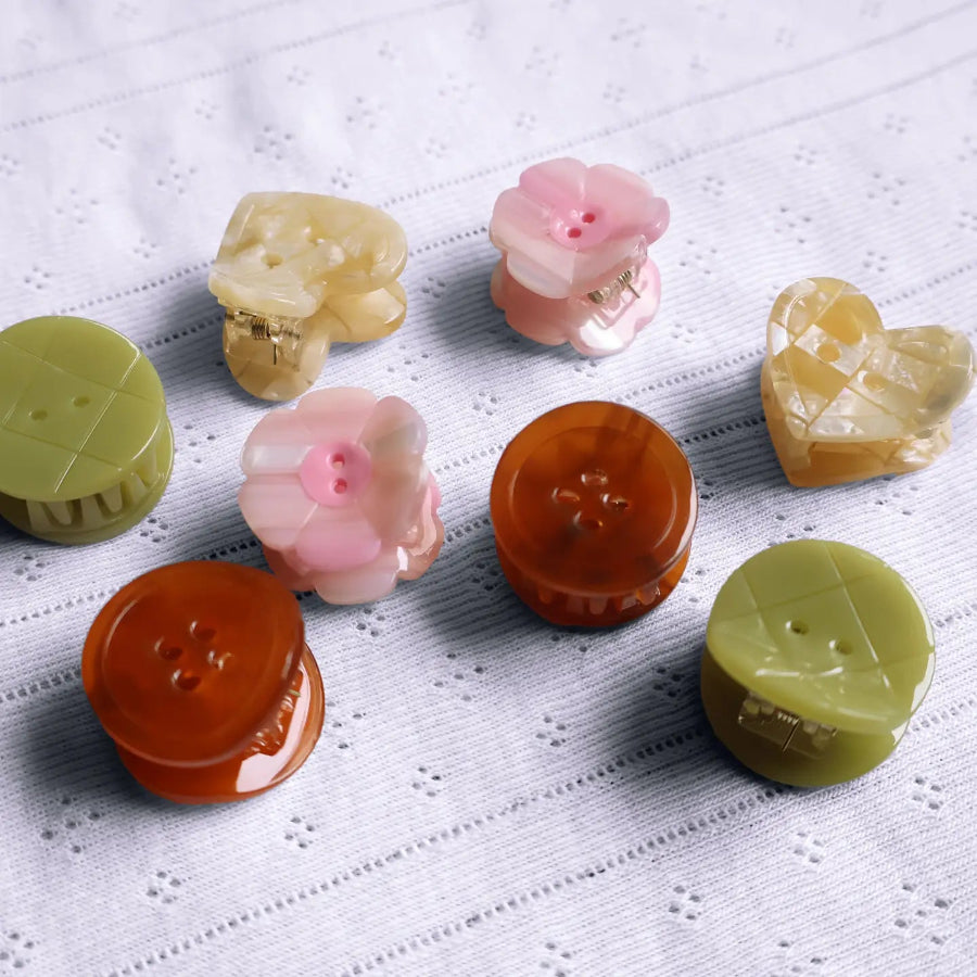 8 little button hair clips on a white background