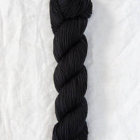 Black yarn skein on a white textured background
