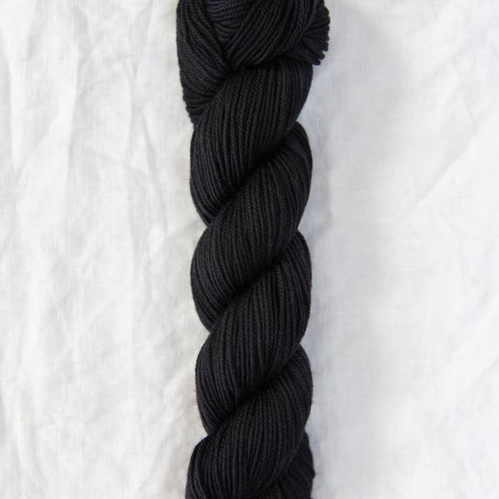 Black yarn skein on a white textured background