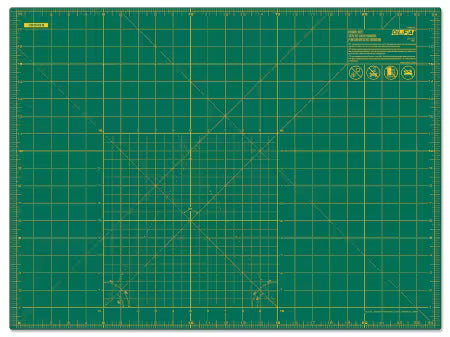Green cutting mat with grid lines and measurements on a white background