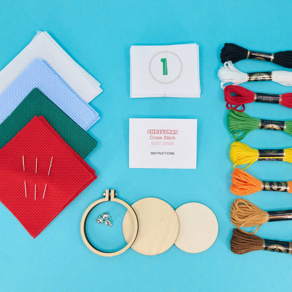 Embroidery kit with fabric, threads, hoop, and needles on a blue background