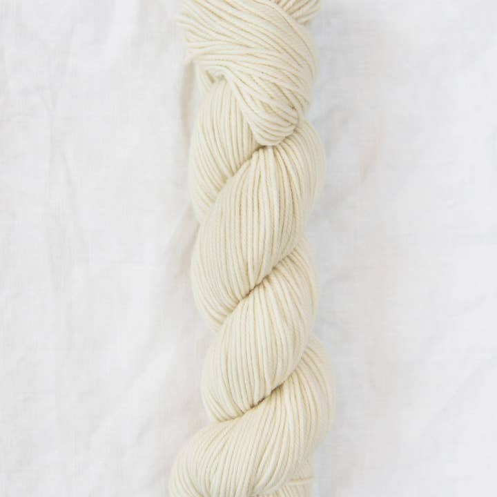 Braided skein of cream-colored yarn on a white background