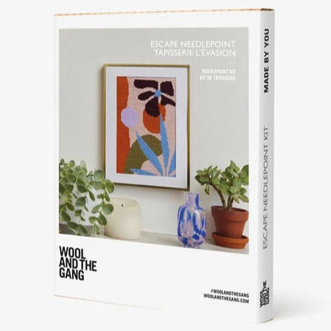 Wool and the Gang needlepoint kit packaging with a framed artwork on a shelf.