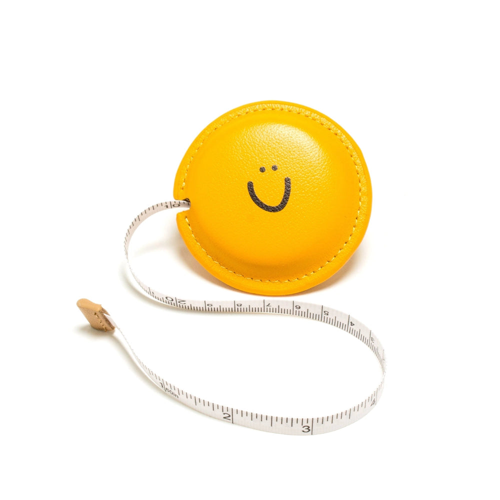 Yellow measuring tape with a smiley face on a white background