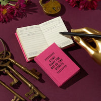 Pink diary with a gold lock, pen, and keys on a purple background