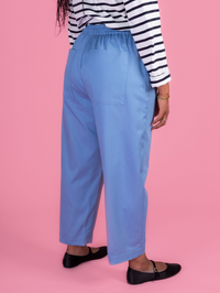 Person wearing blue pants and a striped shirt on a pink background