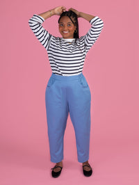 Person wearing a striped shirt and blue pants on a pink background