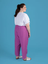 Woman wearing a white shirt and purple checkered pants against a blue background