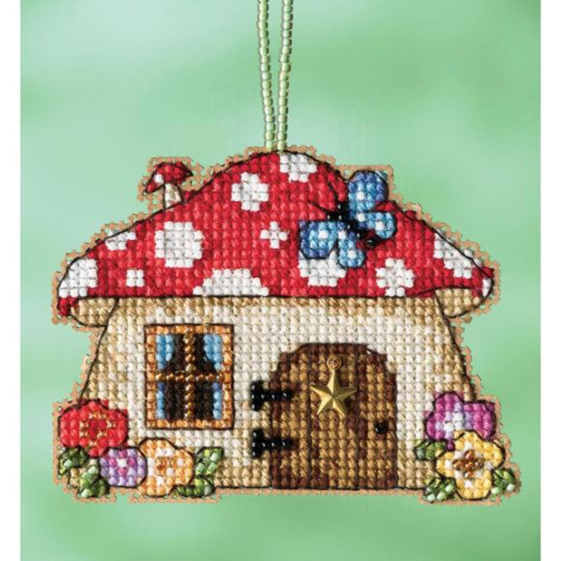 Needlepointed mushroom house ornament with a red roof and white spots on a green background