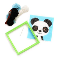 Panda-themed needlepoint kit with a green frame, yarn, and needle on a white background