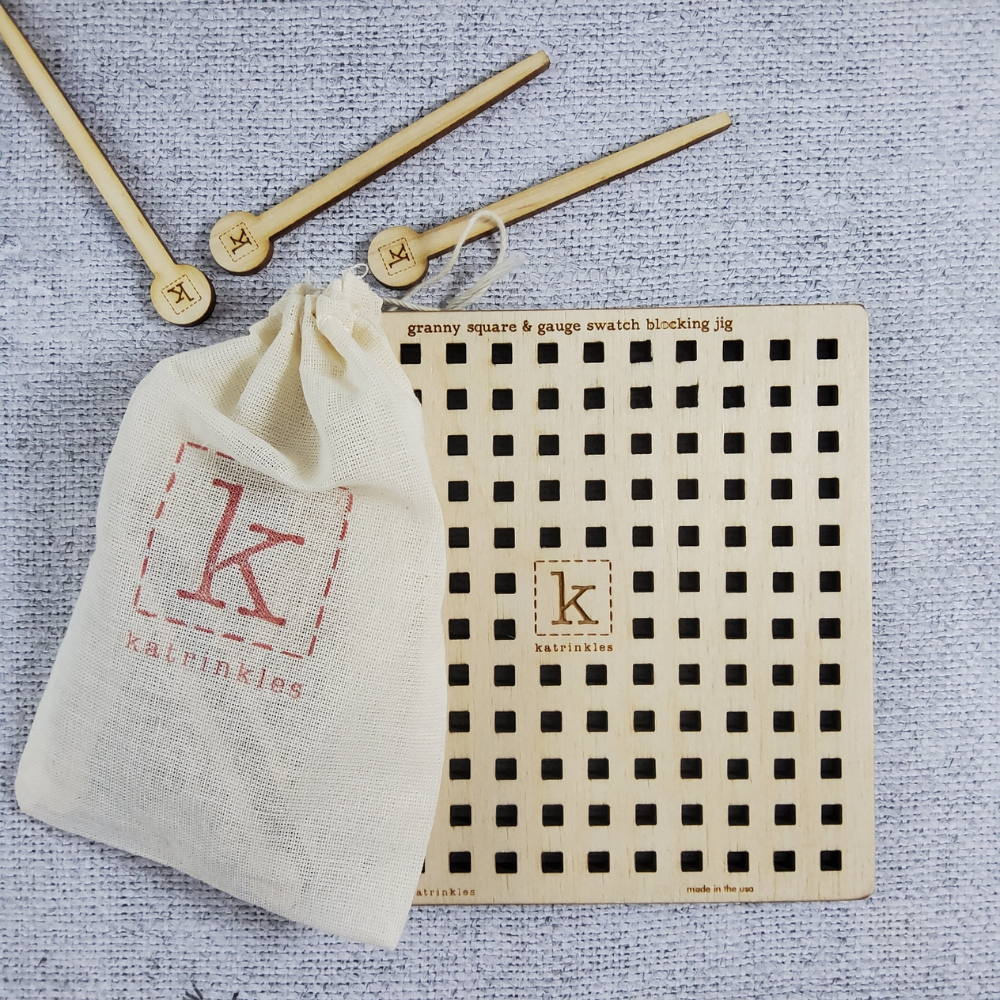 wooden blocking grid with 3 wooden pins next to a white katrinkles pouch