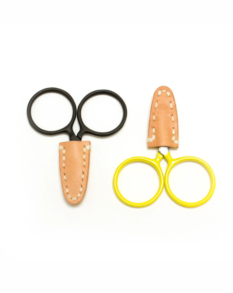 Two pairs of scissors with leather sheaths on a white background