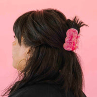 Person with a pink hair accessory clipped in their hair on a pink background