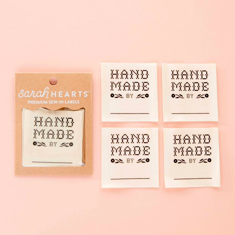 Set of 'Hand Made by' labels with a packaging box on a pink background