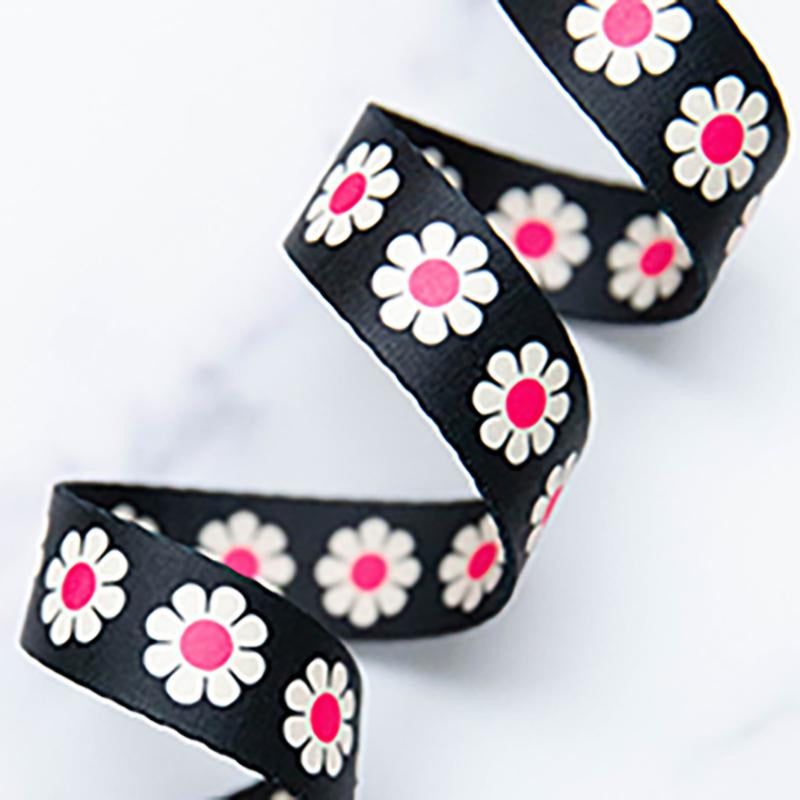 Black webbing with white daisy patterns and pink centers on a light gray background