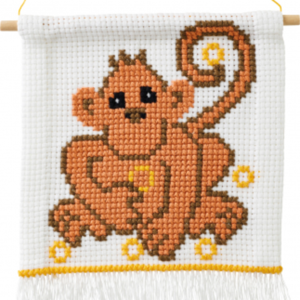Cross stitch project showing a brown monkey with yellow rings. Fabric is on a wooden rod with white fringe on the bottom.
