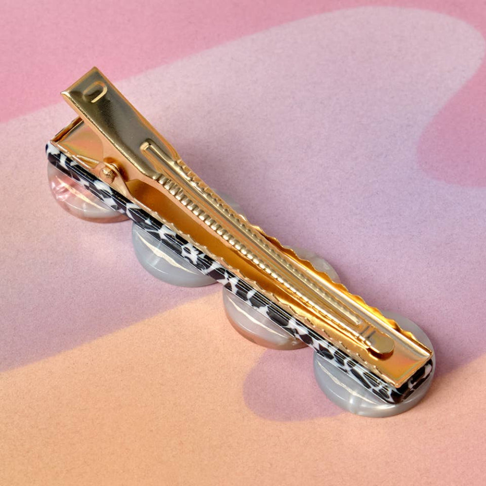 Gold and silver hair clip on a pink and peach gradient background
