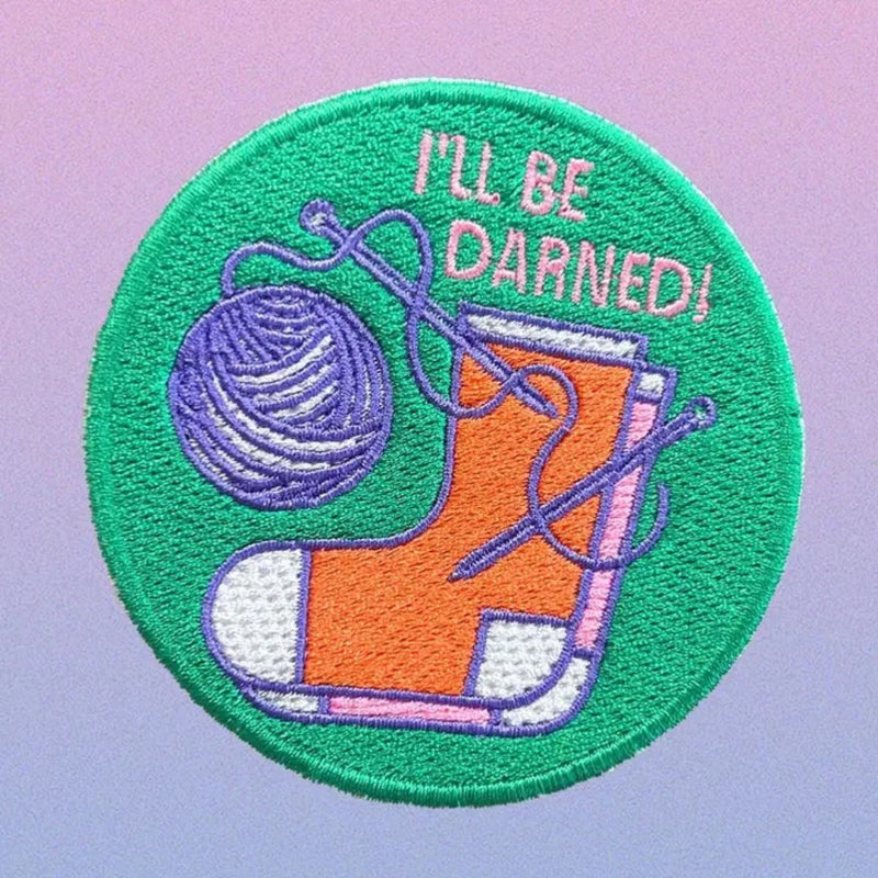 Embroidered patch with a sock, yarn ball, and knitting needles on a green circle with 'I'll Be Darned!' text.