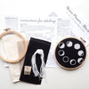 Embroidery hoop with moon phase design and stitching instructions on a white surface