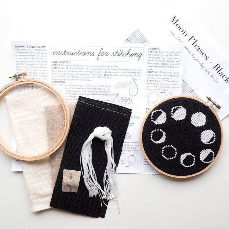 Embroidery hoop with moon phase design and stitching instructions on a white surface