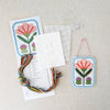 Kit includes beads, canvas, floss, needles, and color printed pattern on a white textured background