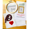 Cross stitch kit with hoop, thread, red heart, and printed instructions on a wooden surface.