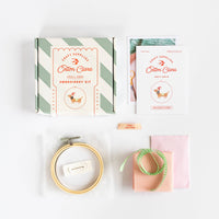 Embroidery kit with hoop, thread, and packaging on a white background