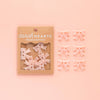 Packaged pink flower buttons with 'sarah HEARTS' branding on a pink background