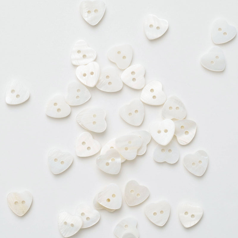 White heart-shaped buttons scattered on a white background