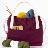 Example of the Town Bag sewing pattern made with purple canvas and white handles used for knitting