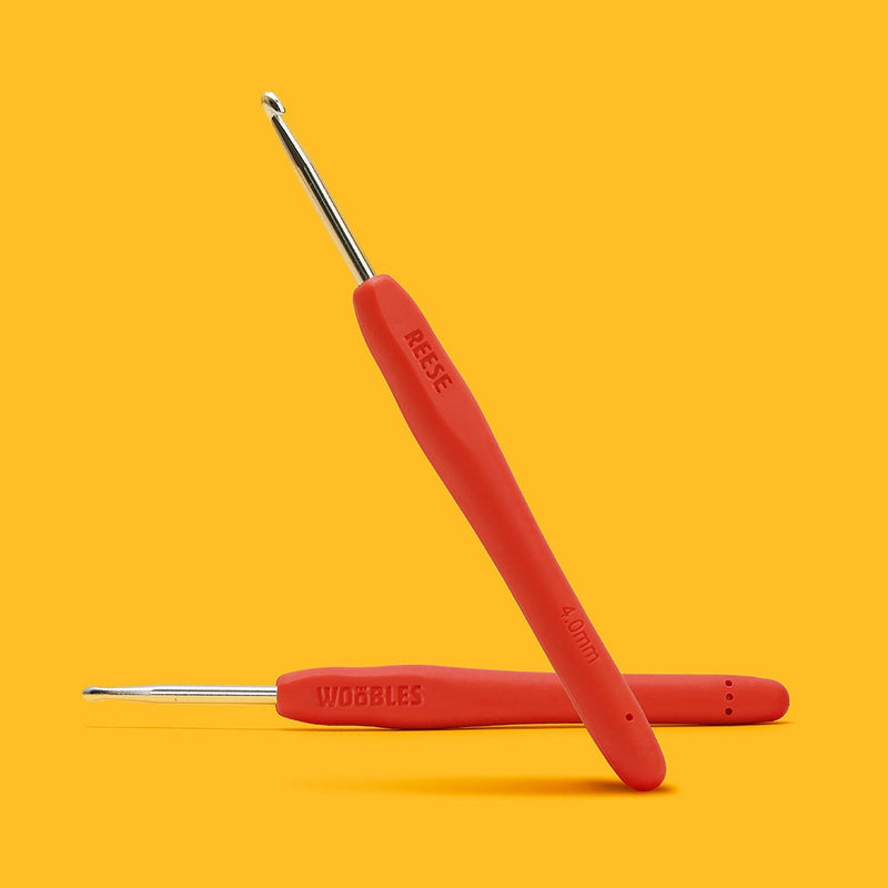 Red crochet hooks with silver ends on a yellow background