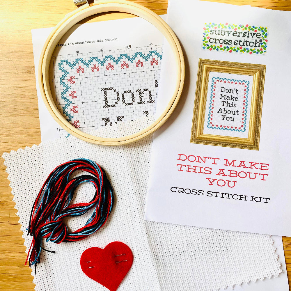 Cross stitch kit with hoop, thread, and printed pattern on a wooden surface