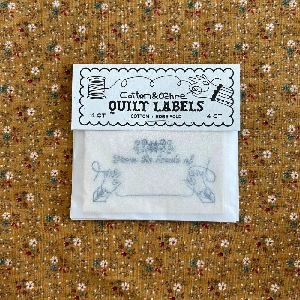 Pack of quilt labels on a floral fabric background