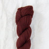 Burgundy skein of yarn on a white background