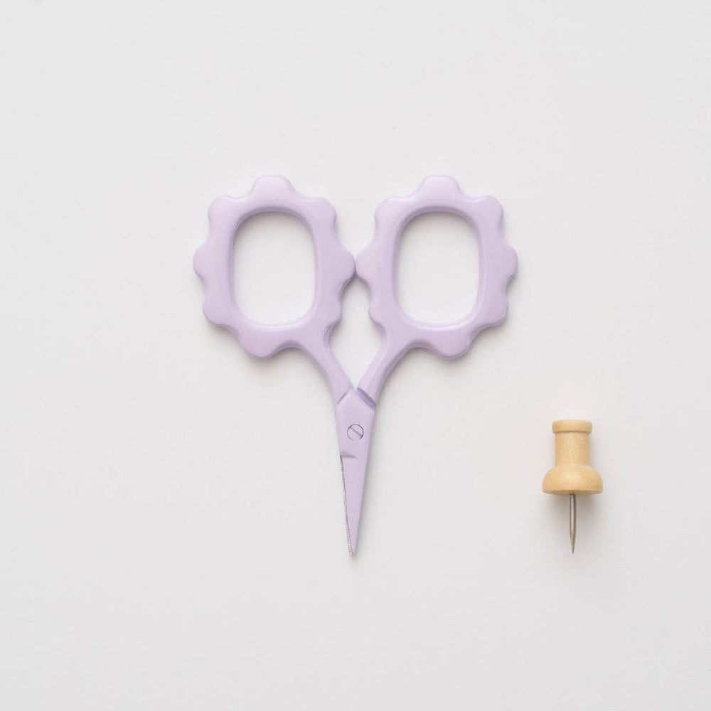 Purple scissors and wooden pin on a light gray background