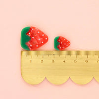 Strawberry-shaped buttons with a ruler on a pink background