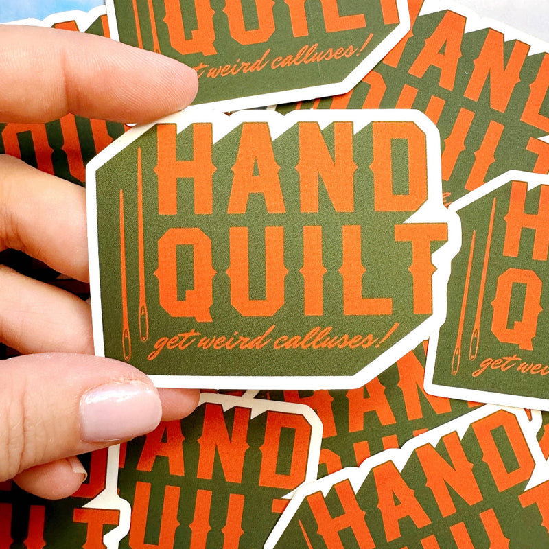 Hand quilt get weird calluses stickers with orange text on green background held by a hand.