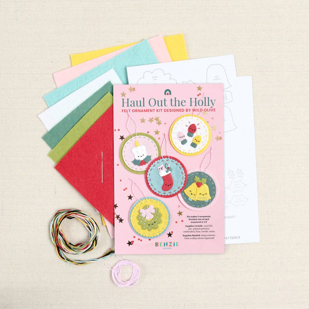 Sheets of felt, pattern, needle, and floss with a "Haul Out the Holidays" label on a white textured background